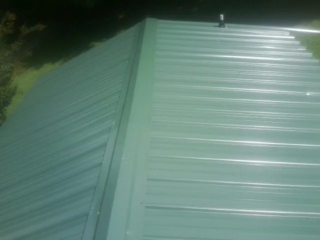 New green metal panels meeting at the ridge of a roof — Flat Roof Repair work by our crew in Roggen