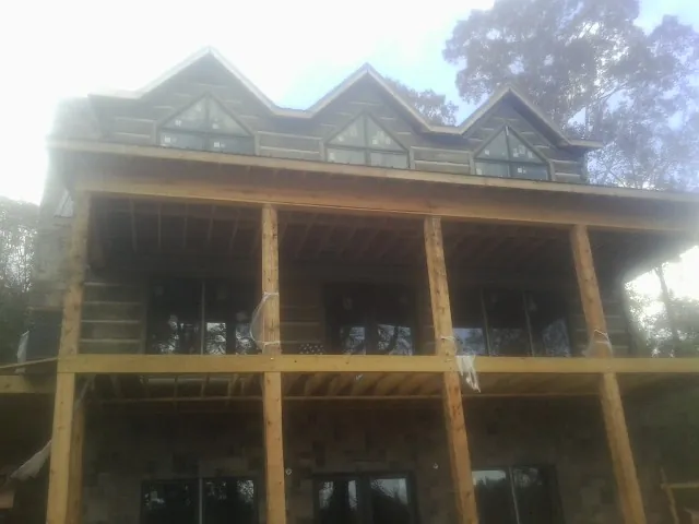 Dormers and porch framing on a large log home under construction — Roof Coating work by our crew in Roggen