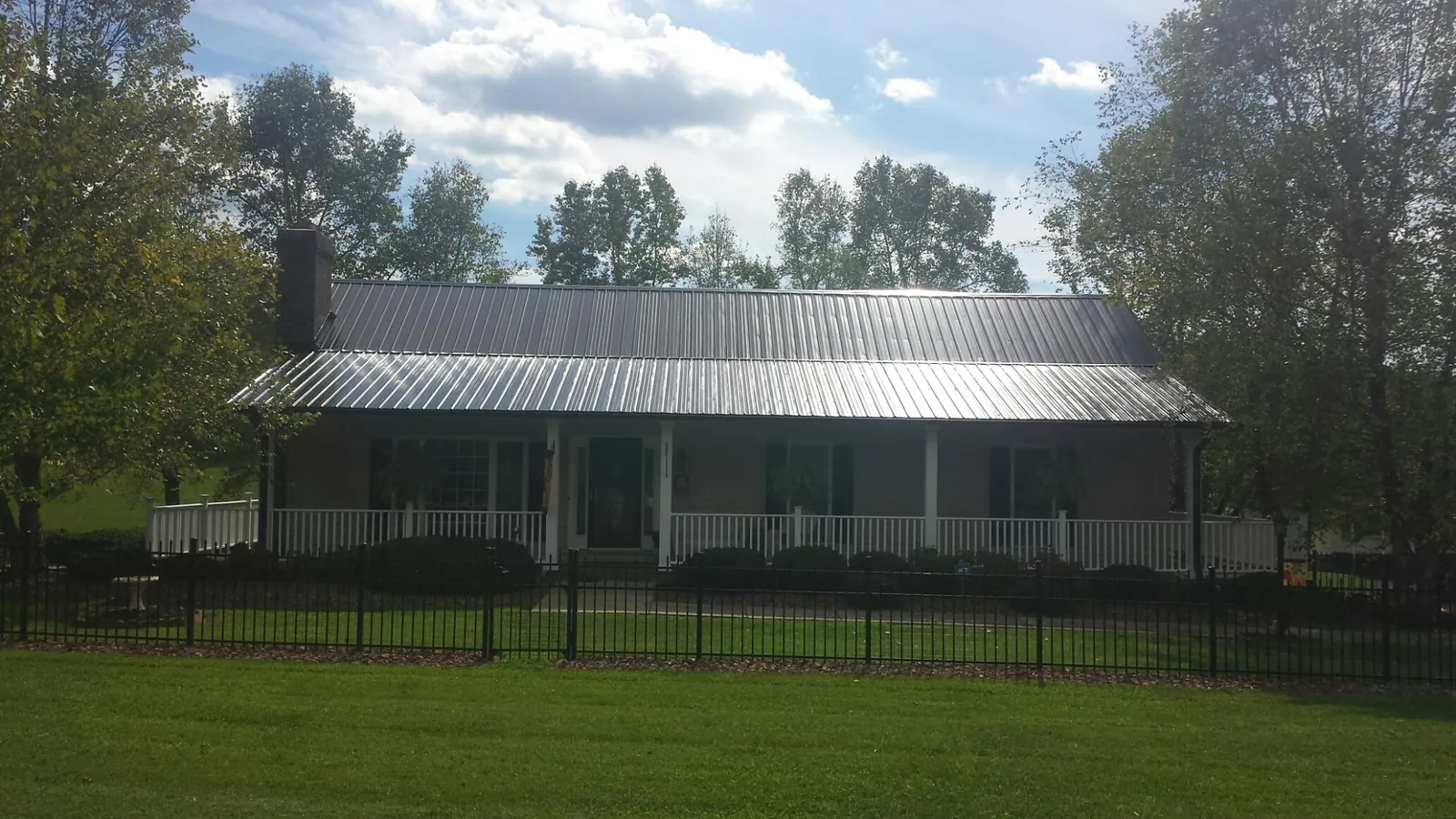 Gray metal roof on a brick ranch with a full width front porch — Gutter Guard Installation work by our crew in Roggen