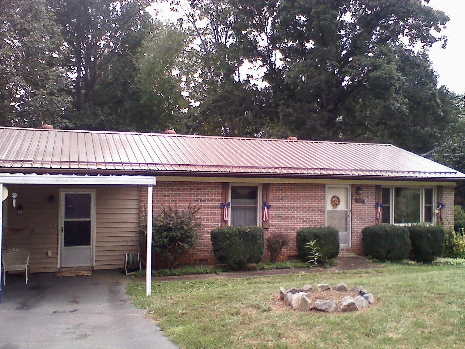 Bronze metal roof and carport on a brick ranch home — Roof Repair work by our crew in Roggen