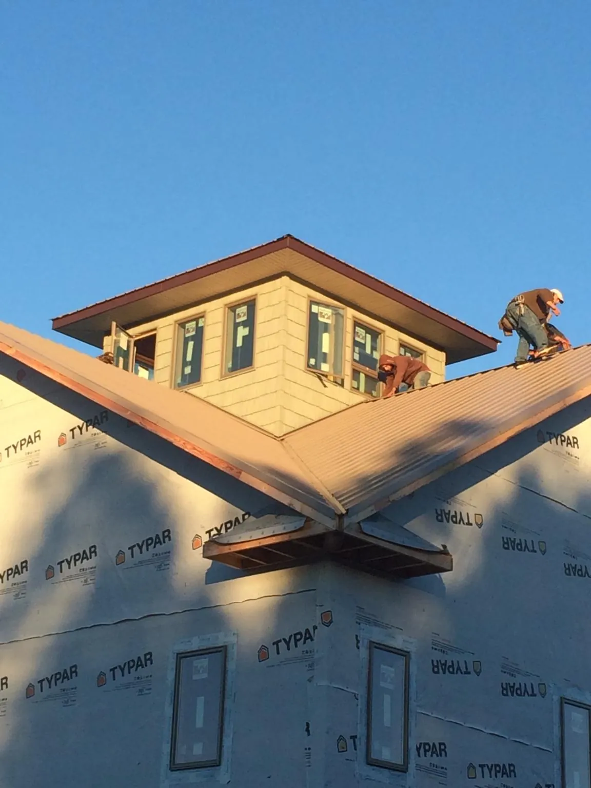 Roofers working around a rooftop cupola on a new metal roof at sunset — Roof Waterproofing in Roggen by Roofing Brothers